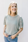 Model wearing a knit sage sweater with eyelet detailed short sleeves. 