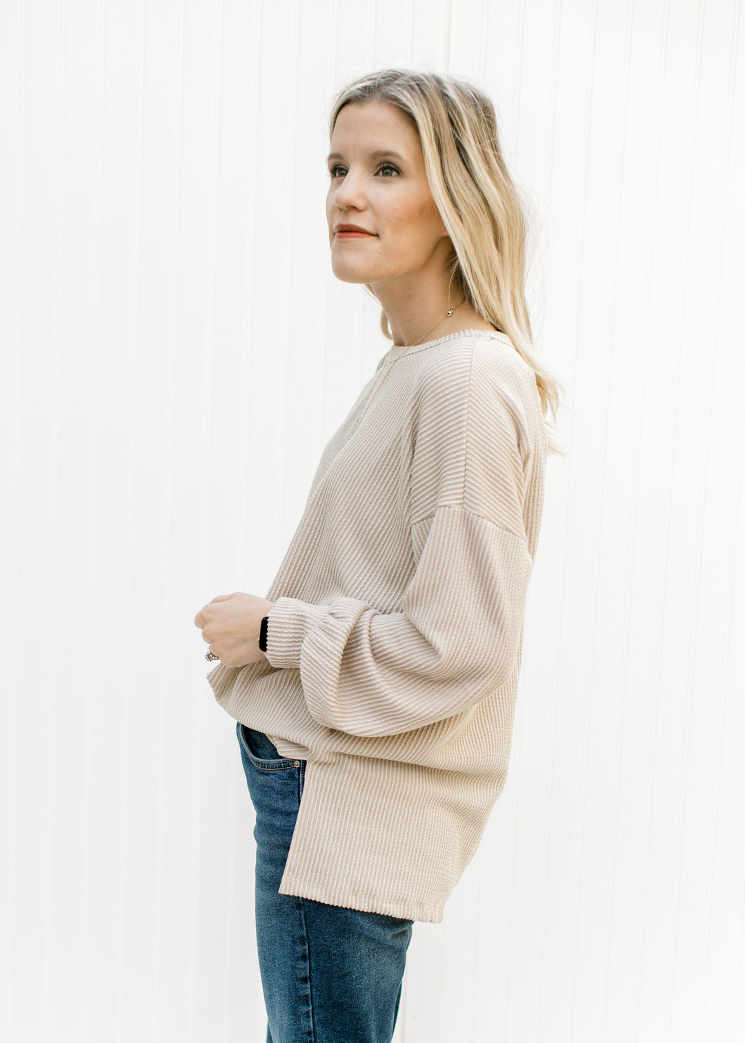 Model wearing a loose fit, tan top with a corded material, long sleeves and split sides. 