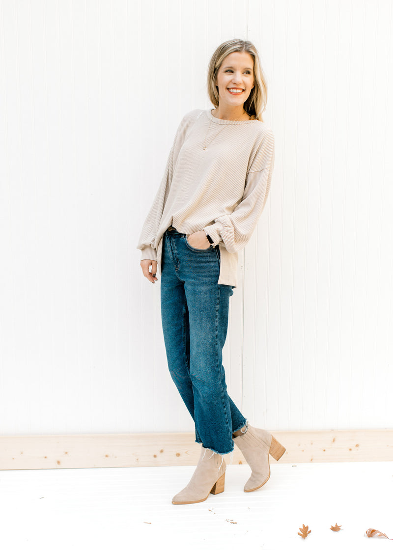 Model wearing jeans, booties and a tan top with a corded material, long sleeves and split sides. 