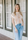 Model wearing jeans and a cream sweater with tan flowers, patch pockets and capped sleeves.