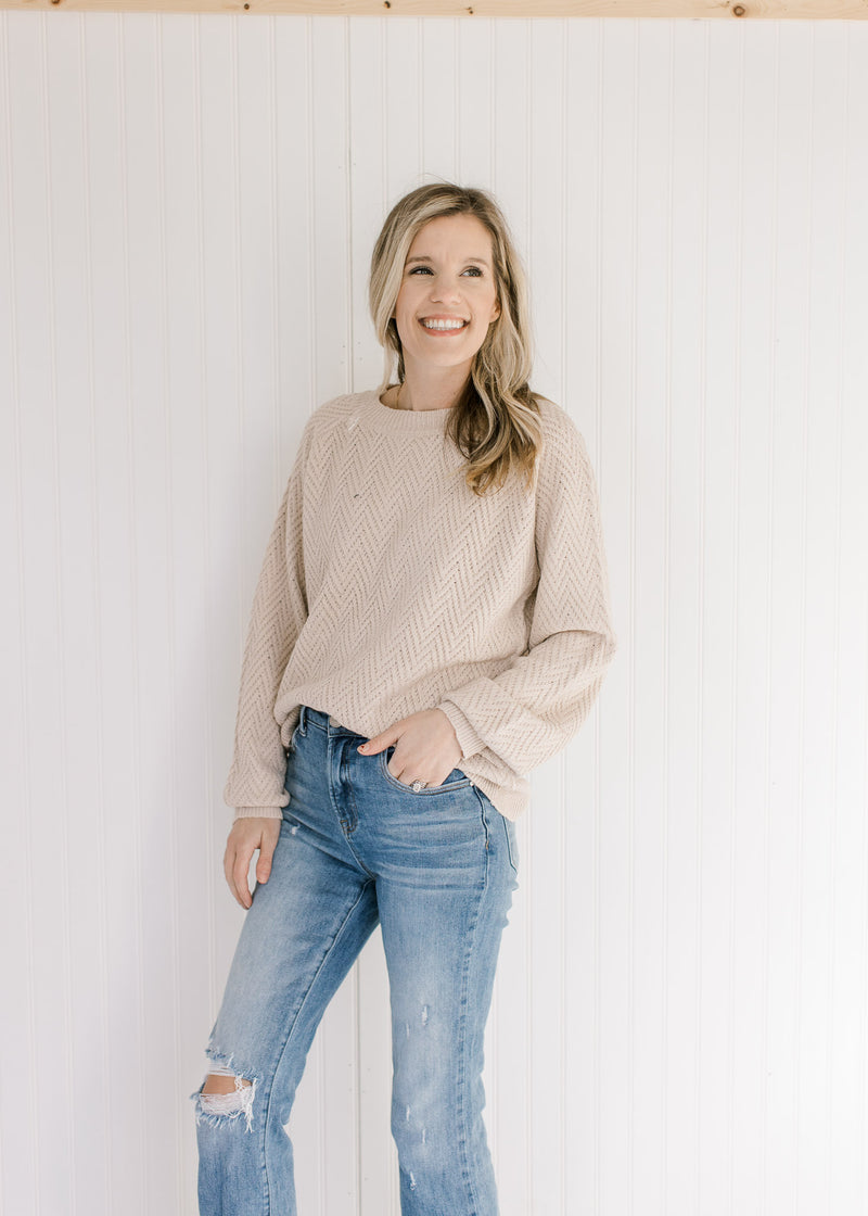 Model wearing jeans with a tan textured sweater with long sleeves and a crew neckline.