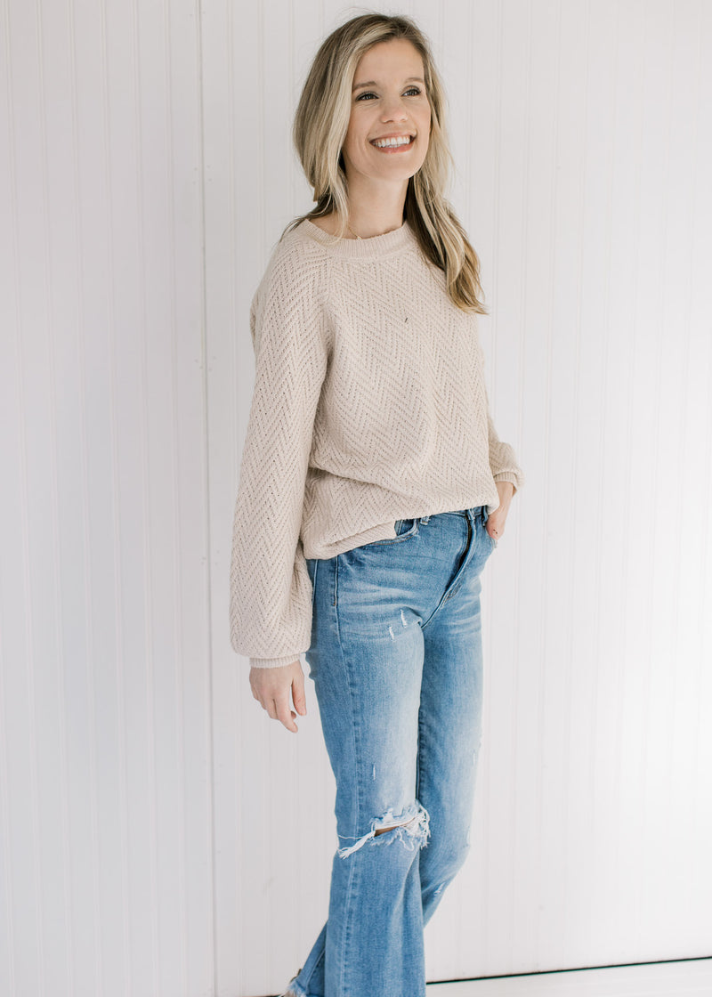 Model wearing a tan textured sweater with bubble long sleeves and a crew neckline.
