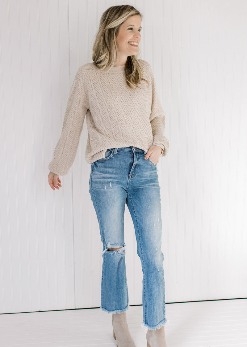 Model wearing jeans, booties and a tan textured sweater with long sleeves and a crew neckline.
