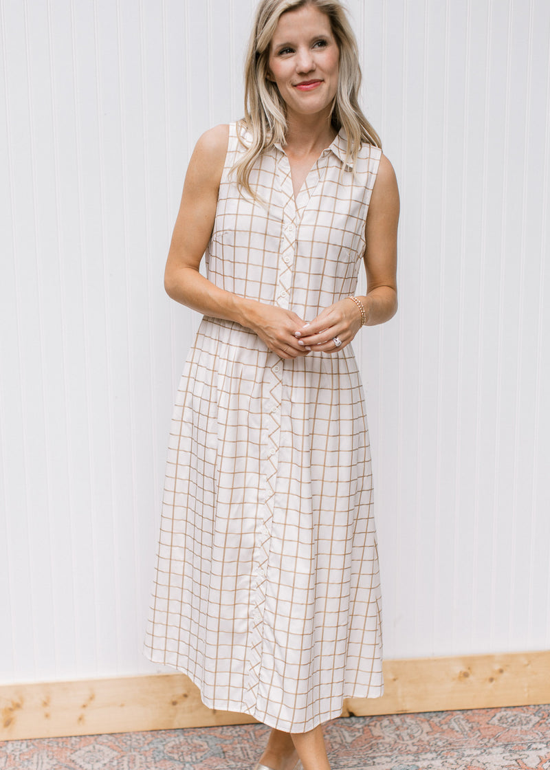 Model wearing a sleeveless cream dress with tan window pane pattern and  button front. 