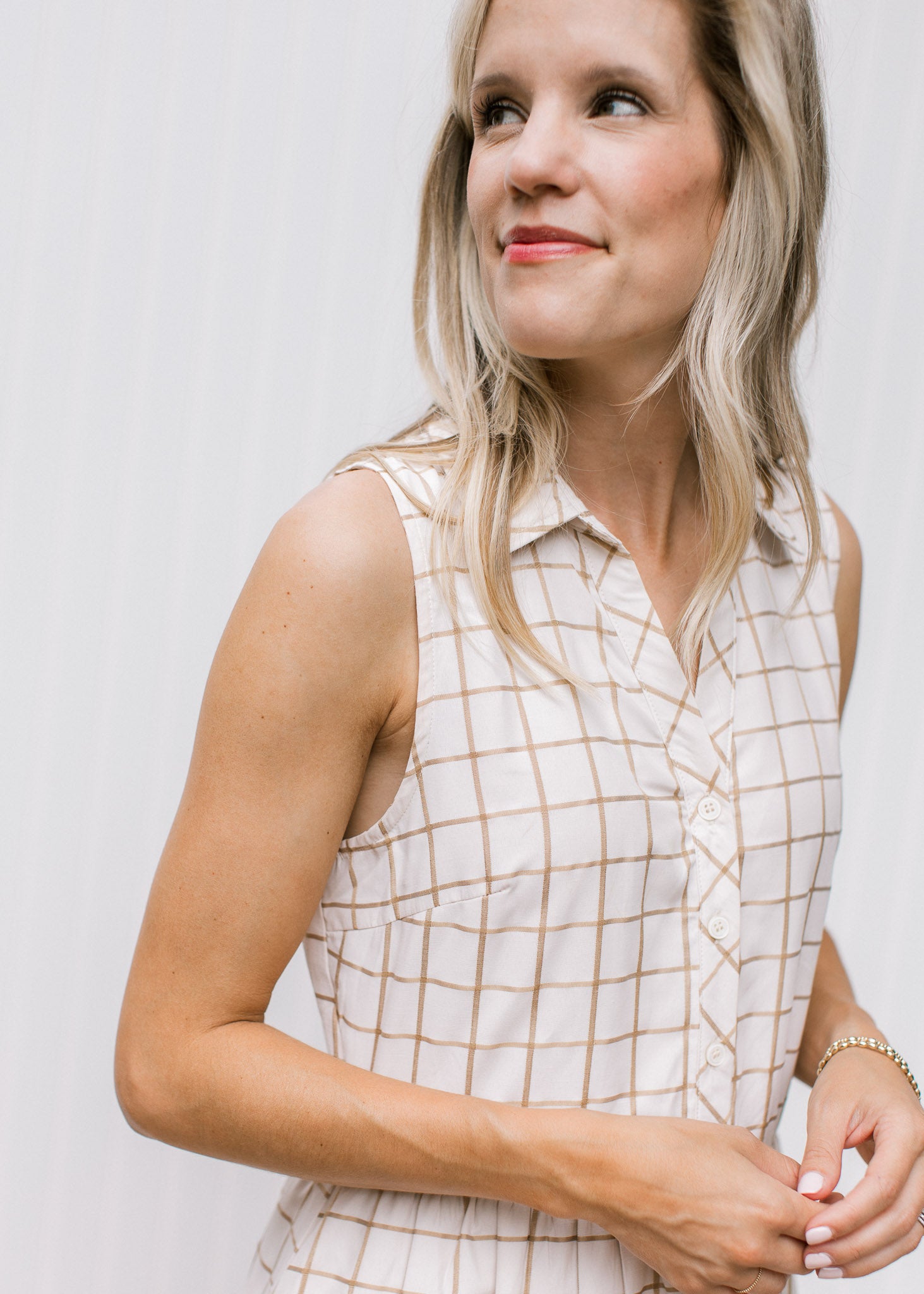 Close up of cream dress with tan window frame pattern, collar and button front. 