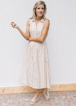 Model wearing wedges with a sleeveless cream dress with tan window pane pattern and button front.