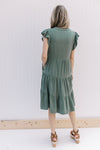 Back view of Model wearing a hunter green tiered midi with ruffle cap sleeves and pockets.