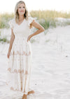 Model is wearing a cream v-neck dress with taupe floral, smocked bodice and ruffle cap sleeve. 
