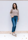 Model wearing jeans and mules with a taupe long sleeve sweater with cream zig zag stripes. 