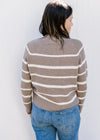 Back view of Model wearing a taupe sweater with white stripes with long sleeves.