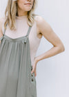 Model wearing a taupe ribbed body suit with a mocked neckline and a two snap closure. 