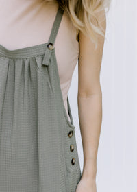 Close up of Model wearing a taupe ribbed body suit with a mocked neckline and a two snap closure. 