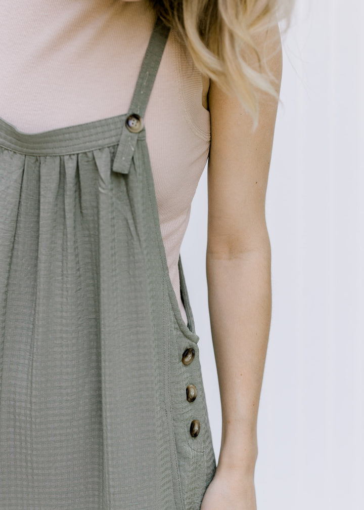 Close up of Model wearing a taupe ribbed body suit with a mocked neckline and a two snap closure. 