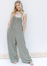 Model wearing a sage jumpsuit with taupe bodysuit with a mocked neckline and a two snap closure. 