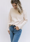 Model wearing jeans with a taupe and white checkered sweater with long sleeves and a round neck. 