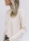 Model wearing a long sleeve taupe and white checkered sweater with ribbed neck, hem and cuff. 