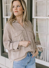 Model wearing a taupe button down top with patch pockets and long sleeves with 3/4 clasp. 