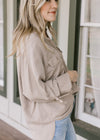 Close up of clasp on the sleeve of a taupe button up top with patch pockets and tencel material. 