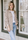Model wearing white top, jeans and a taupe button down top with patch pockets and long sleeves.