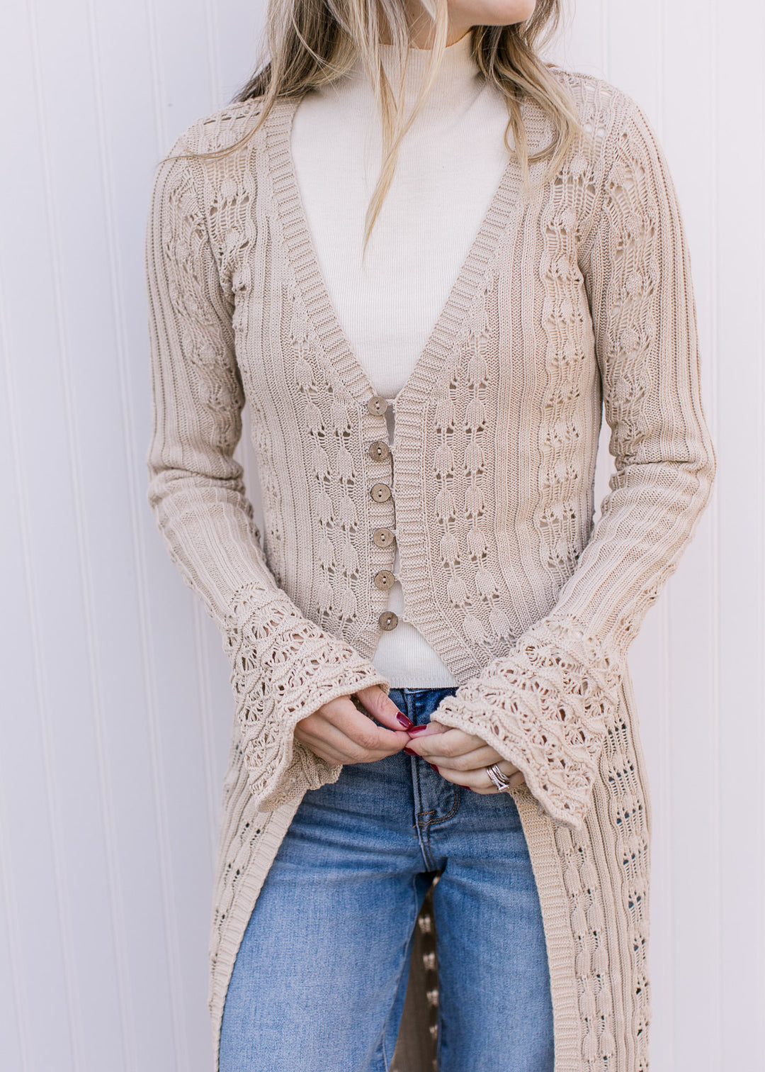 Close up of button closure and bell long sleeves on a taupe cardigan with a v-neck. 