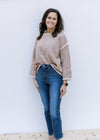 Model wearing jeans with a taupe sweater with cream hem lines, rolled hem and long sleeves. 