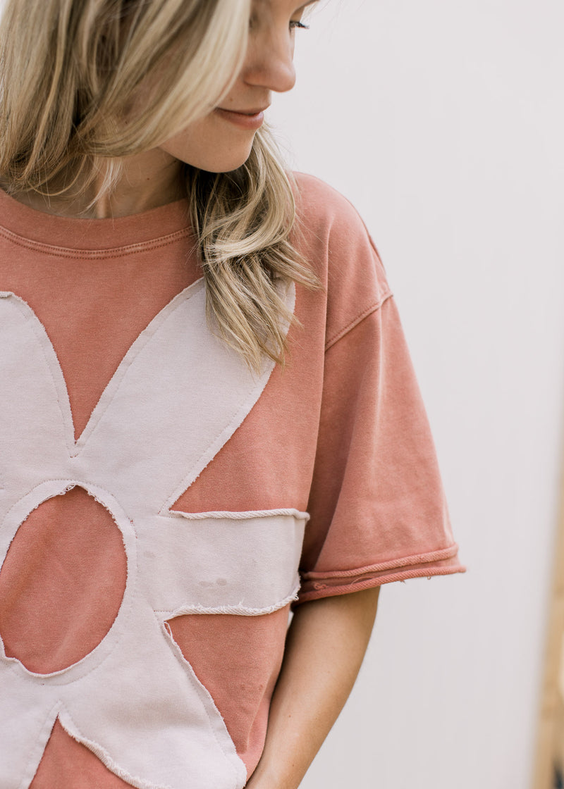 Close up of cream flower with raw hem and a dusty peach top with short sleeves. 