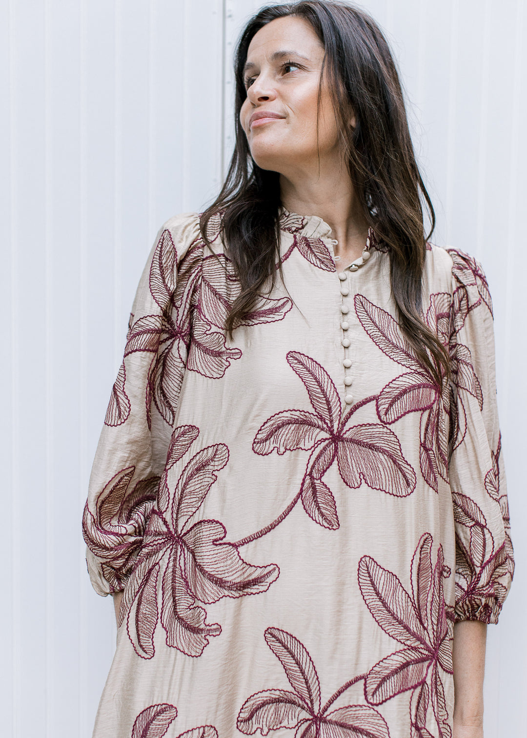 Front detail of taupe embroidered dress with burgundy floral motifs, covered buttons and three-quarter bubble sleeves.