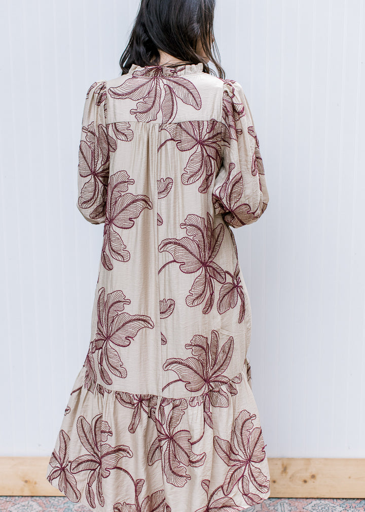 Back view of taupe midi dress with burgundy floral embroidery, gathered back yoke, bubble sleeves and ruffled hem.