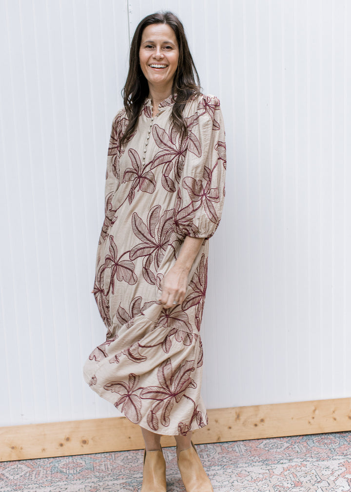 Taupe embroidered midi dress with burgundy floral motifs and ruffled hem, styled with tan ankle boots.