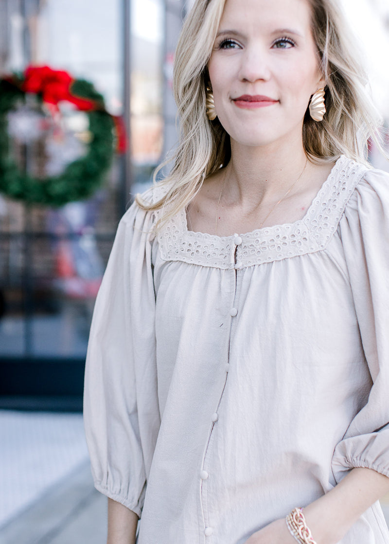 Cloe up of eyelet lace detail along the square neck of a taupe button top with 3/4 sleeves. 