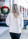 Back view of Model wearing a taupe top with lace detail at neck and 3/4 bubble sleeves. 