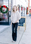 Model wearing jeans, boots and a taupe top with eyelet lace detail at neck and 3/4 sleeves. 