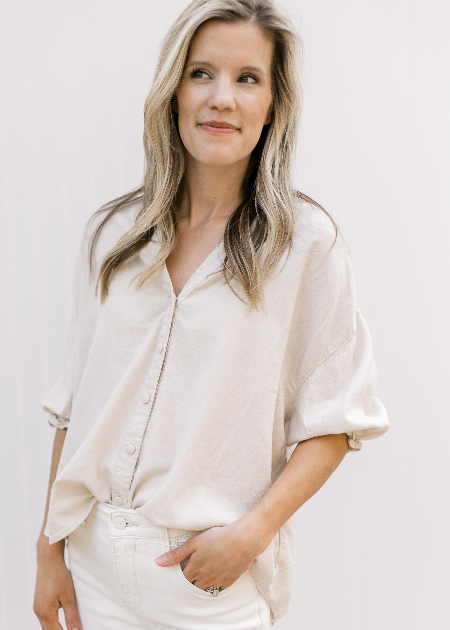 Model wearing a taupe button up top with 3/4 elastic sleeves and a collar. 