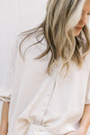 Close up of buttons on a taupe linen top with 3/4 sleeves with elastic. 