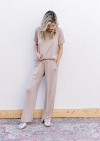 Model wearing a taupe set with a short sleeve crew neck top and wide leg bottoms. 