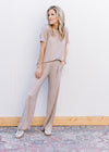Model wearing sneakers with a taupe set with a short sleeve crew neck top and wide leg bottoms. 