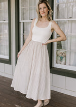 Model wearing a midi with scalloped cream ribbed sweater top and taupe skirt with black stripes. 