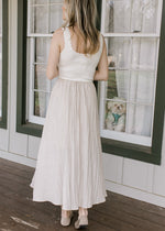 Back view of Model wearing a midi with cream ribbed sweater top and taupe skirt with black stripes. 