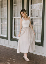 Model wearing flats and a midi with a cream ribbed top and taupe skirt with black stripes. 