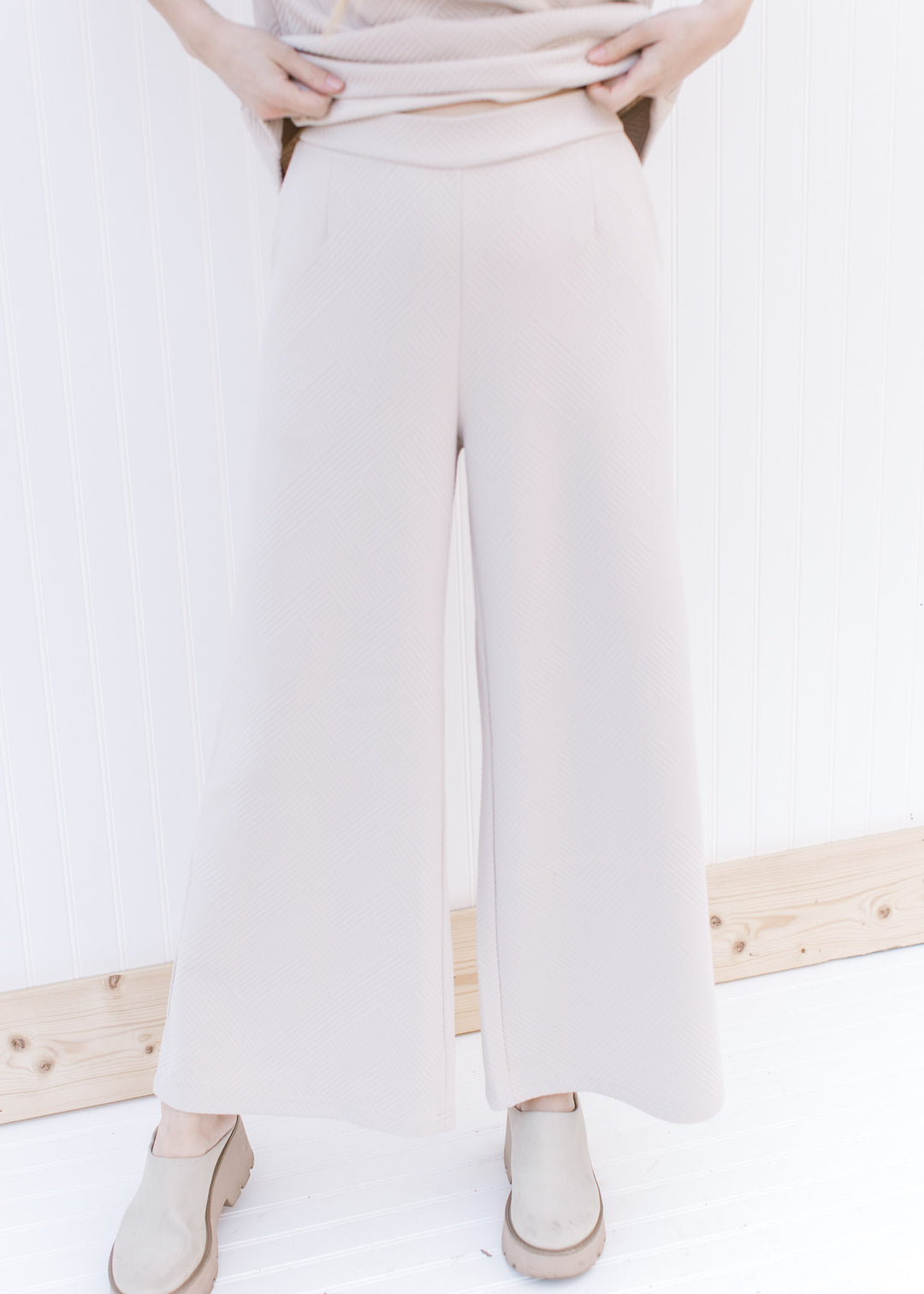 Model wearing a textured taupe wide leg pants, part of a set with short sleeve top.
