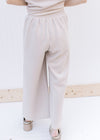 Back view of Model wearing a textured taupe wide leg pants, part of a set with short sleeve top.