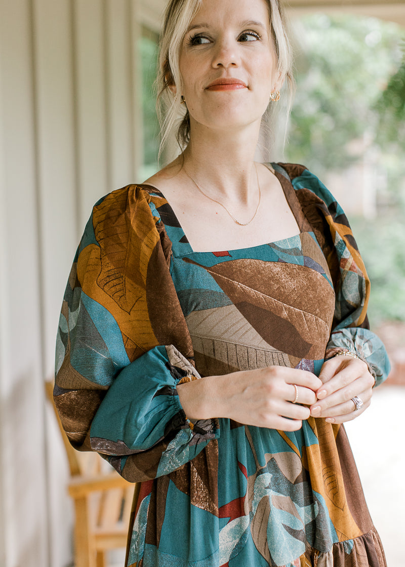 Close up of bubble long sleeves and square neck on an espresso colored dress with floral. 