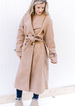 Model wearing an ultra cozy camel jacket with a belt, flap collar, long sleeves and a knee length. 