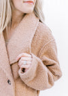 Close up of flap color on a camel colored jacket with a double breast detail and a knee length. 