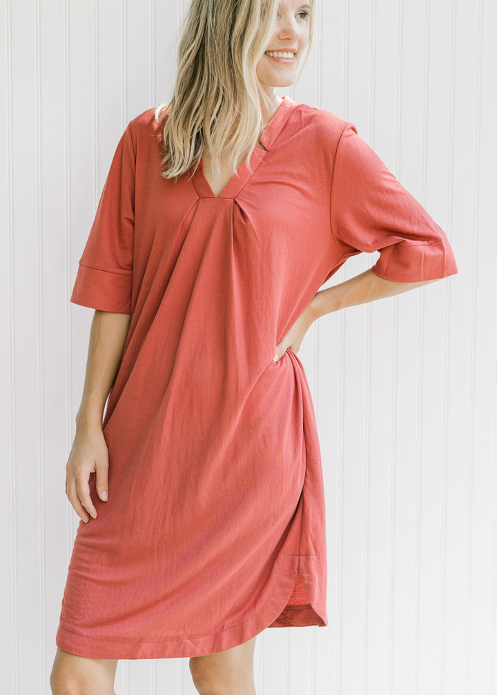 Model wearing a lightweight burgundy dress with a notch v-neck, short sleeves and pockets. 