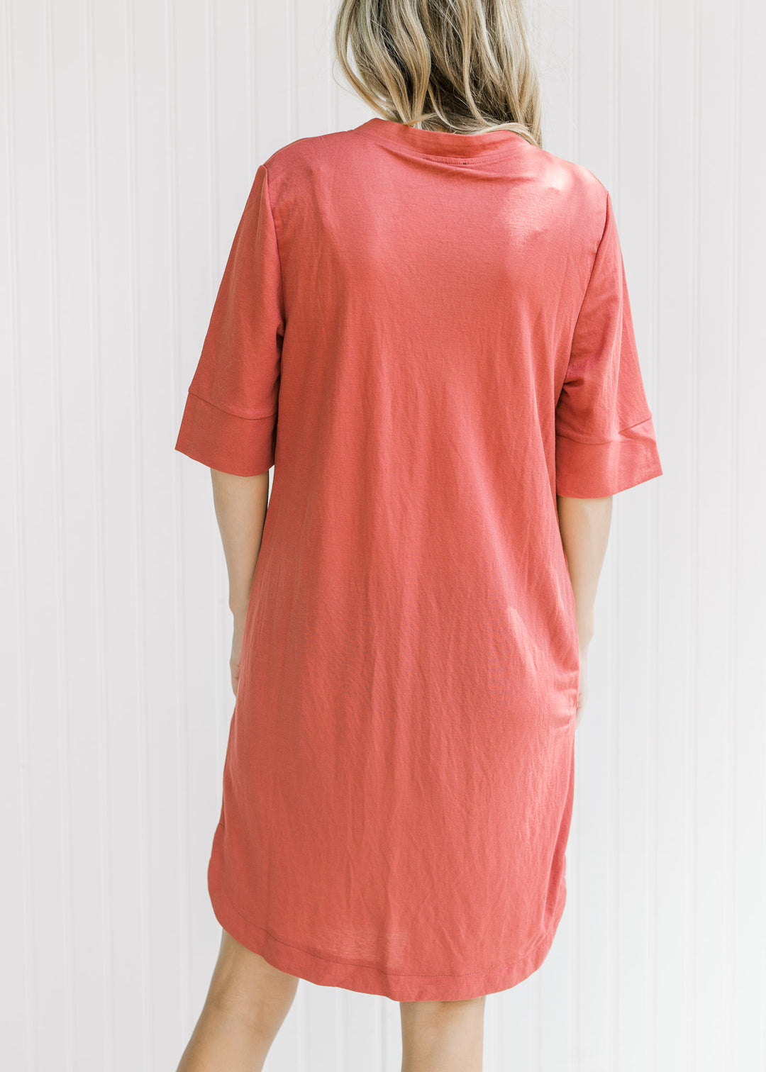 Back view of Model wearing a burgundy dress with a notch v-neck, short sleeves and pockets. 