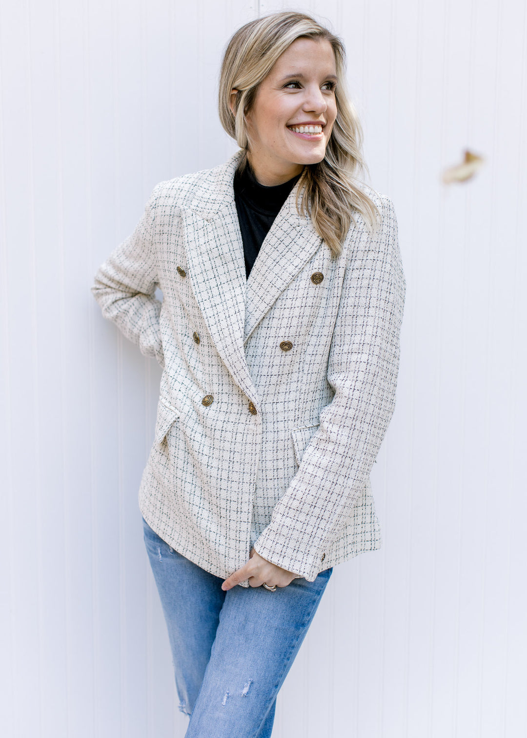 Model wearing a cream plaid blazer with gold double breasted buttons and faux flap pockets. 
