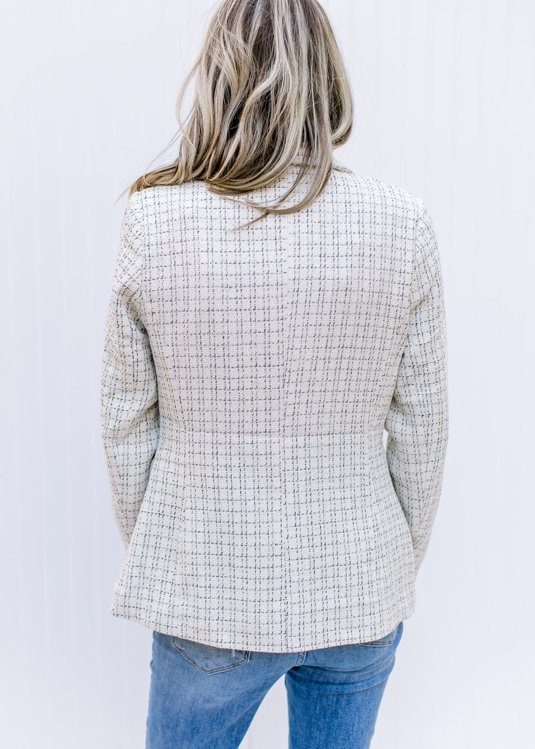 Back view of Model wearing a cream plaid blazer with gold double breasted buttons and long sleeves.