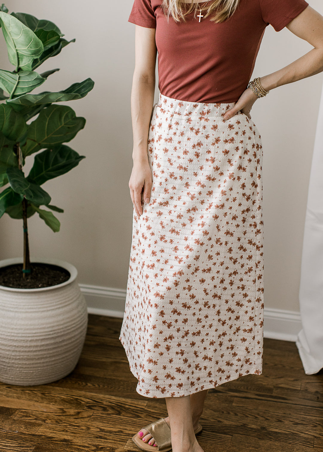 Model wearing a cream midi skirt with rose floral print, textured material and an elastic waistband.