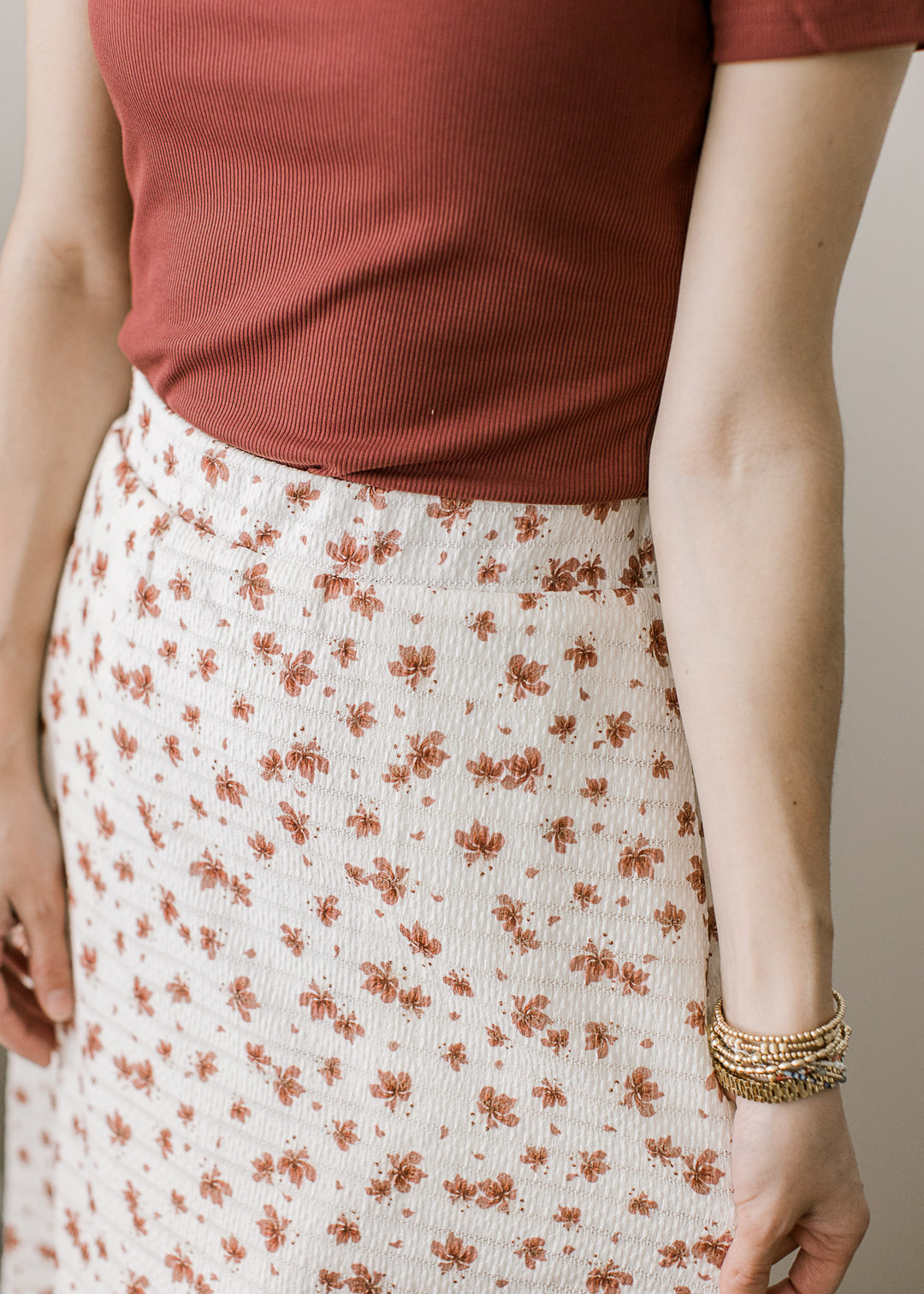 Close up view of textured material and elastic waistband on an cream midi skirt with rose floral.